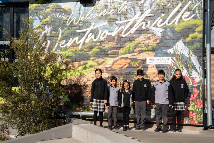 line of students standing in front of school mural