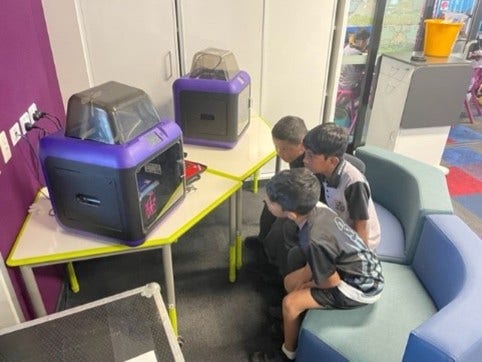 3 students looking at 3D printers
