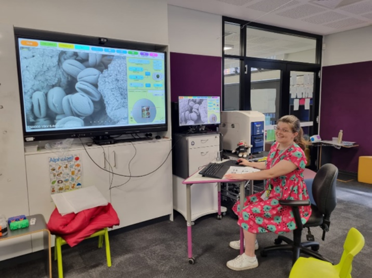 Seated female teacher in classroom with image projected onto wall