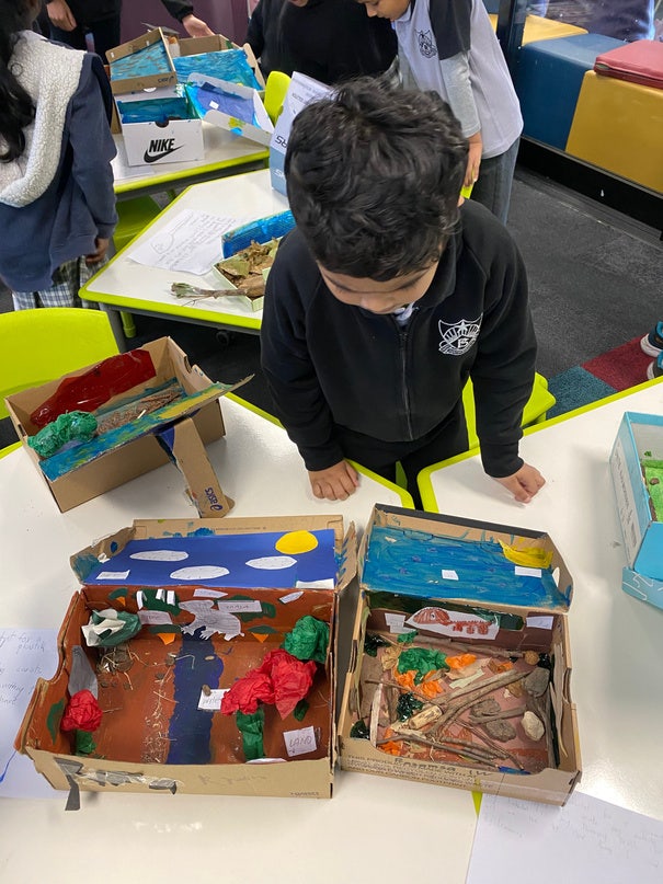 Male student bending over project in shoebox