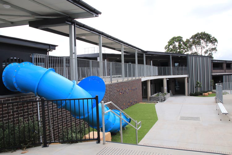 Blue cylindrical slippery dip leading to play area at the school