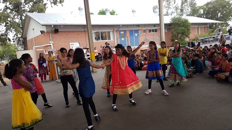 Students dressed in colourful clothing dancing in outdoor area