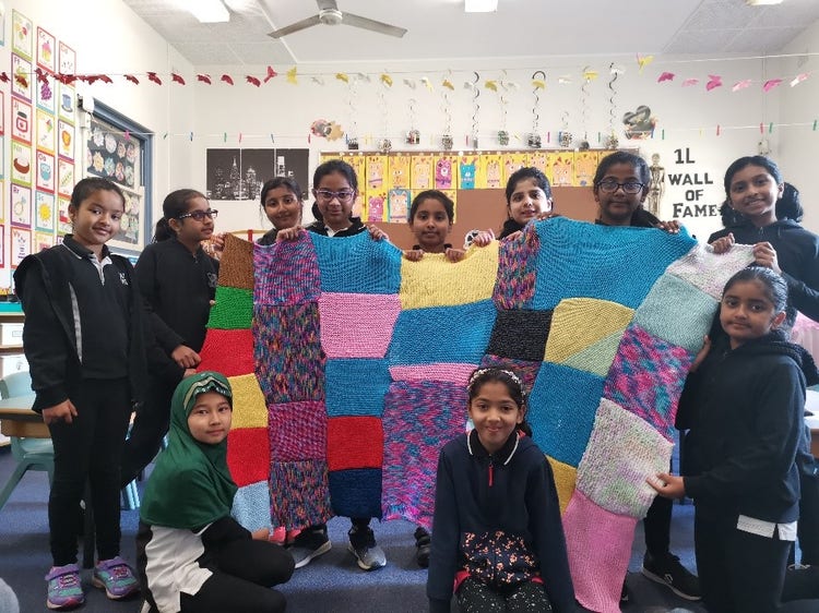 Students holding up colourful knitted squares