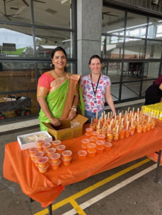 Two adult females standing with orange coloured food ready to serve