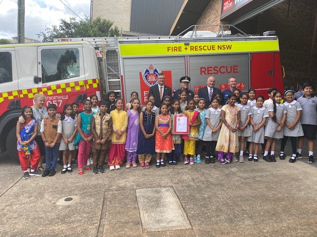Students dressed colourfully standing in front of a fire engine with firefighters