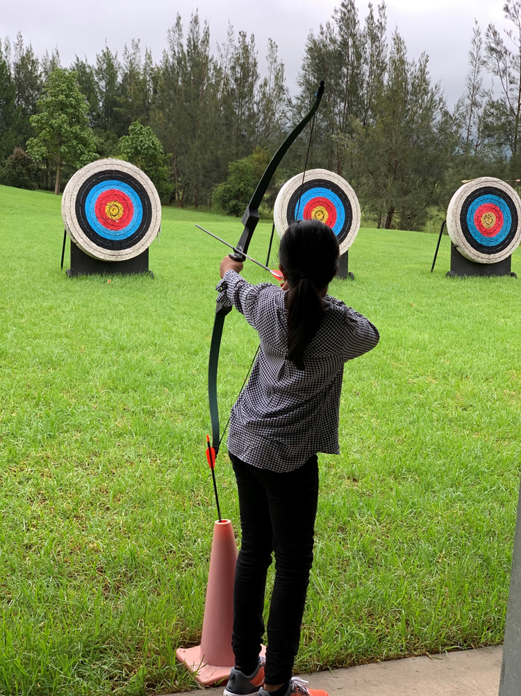 Student doing archery in front of three bullseyes